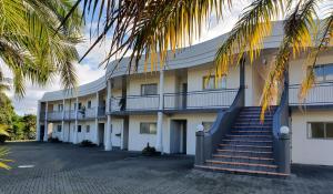 a building with stairs and a palm tree at Breakers Motel in Whangamata