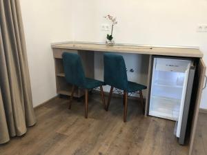 a desk with two chairs next to a refrigerator at Aparthotel Plevnei1 in Cluj-Napoca