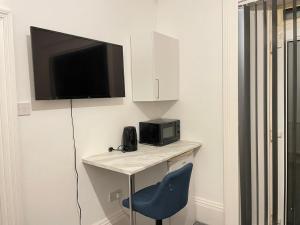 a room with a desk with a television and a chair at St Peter's Shared House in Birmingham