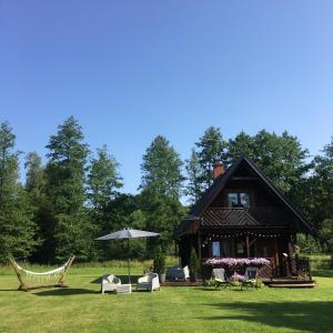 ein Haus mit Stühlen und einem Regenschirm im Gras in der Unterkunft Monasteria in Stare Monasterzysko