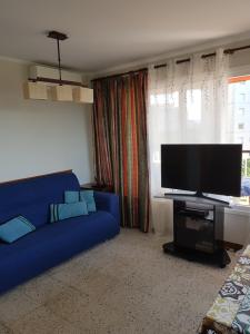 a living room with a blue couch and a flat screen tv at Apartamento en la torre de S`Abanell in Blanes