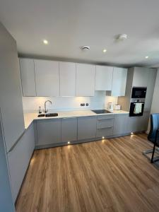 a kitchen with white cabinets and a wooden floor at City Centre Luxury Apartments in Belfast