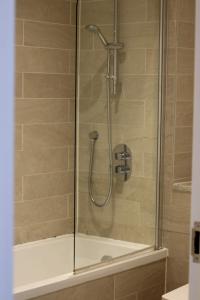 een douche met een glazen deur en een bad bij City Centre Luxury Apartments in Belfast