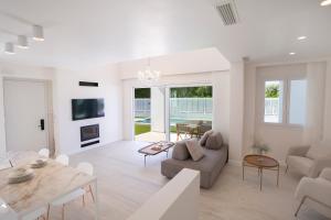 un soggiorno bianco con tavolo e divano di THE QUAD Luxury Villas a Lygia