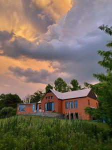 ein Haus auf einem Feld mit wolkigem Himmel in der Unterkunft Eden's Echoes Country Retreat in Blacksburg