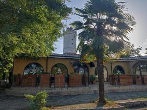 a building with a clock tower and a palm tree at Частный дом Ленкорань in Lankaran