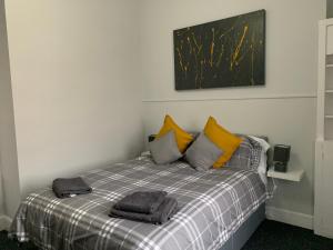 a bedroom with a bed with yellow and gray pillows at Nelson st (VIEWPARK) in Largs