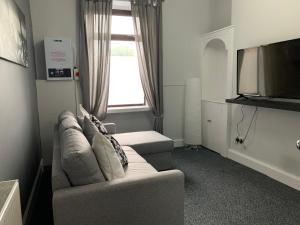 a living room with a couch and a flat screen tv at Nelson st (VIEWPARK) in Largs