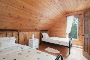 a bedroom with two beds in a wooden cabin at Chalet Bonheur -Rustique- Pet friendly in Rivière-Rouge