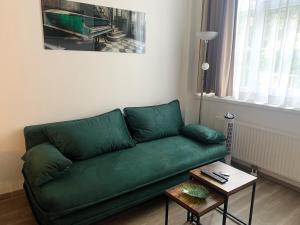 een groene bank in een woonkamer met een tafel bij Apartment Philip Vienna Self Check-In in Wenen