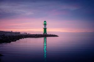 a green and white lighthouse sitting on the edge of the water at Kapitaenshaus in Wasserlage! Traumapartments Warnemuende in Warnemünde +50 photos