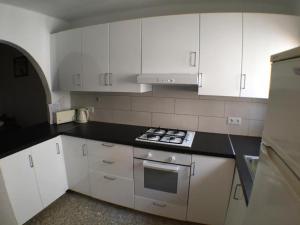 uma cozinha com armários brancos e um forno com placa de fogão em Garden Apartment, La Noria em Málaga