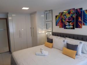 a bedroom with a white bed with a painting on the wall at Arraial do Cabo. Conforto, Piscina, Vista Mar. in Arraial do Cabo +52 photos