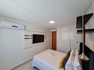 a white room with a bed and a tv at Arraial do Cabo. Conforto, Piscina, Vista Mar. in Arraial do Cabo