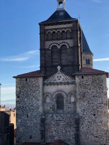 einen hohen Turm mit einer Uhr darüber in der Unterkunft Charmant T2 Cosy Notre Dame du Port in Clermont-Ferrand