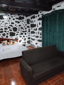 a bedroom with a bed and a couch in front of a stone wall at MAGMA RRAL3529 in Velas