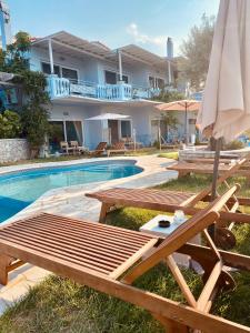 een zwembad met een tafel en een parasol naast een huis bij Sunny Place Resort Kilada in Kilada