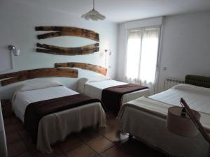 Habitación de hotel con 3 camas y ventana en Casa Rural Nemesio, en Iturmendi