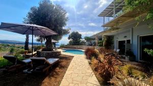 a patio with chairs and an umbrella next to a house at Sunny Place Resort Kilada in Kilada