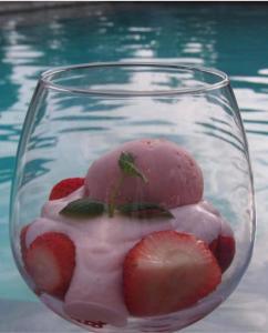 a glass bowl filled with strawberries in front of a pool at Palmita Hotel Hostel in Oranjestad