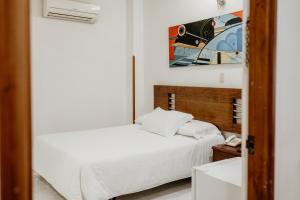 a white bedroom with a bed and a phone at Hotel Barrancabermeja Plaza in Barrancabermeja