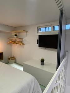 1 dormitorio con 1 cama y TV en la pared en Precioso loft en centro histórico de Melilla en Melilla