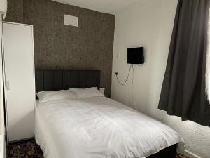 a bedroom with a white bed with a tv on the wall at Sam Residence Hotel in Blackpool