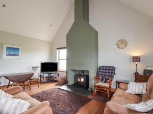 a living room with a couch and a fireplace at Ridge End Cottage in Kilmaluag