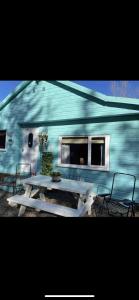 a picnic table in front of a blue building at Cabin with Hot Tub in Aberdeenshire in Gamrie