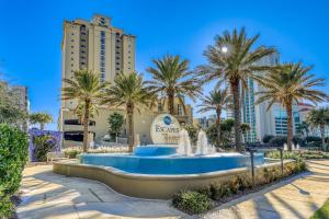a fountain in front of a resort with palm trees at Escapes! To The Shores #204 in Orange Beach