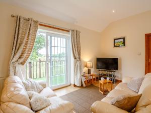 a living room with two couches and a large window at 2 Black Horse Cottages in Pentraeth