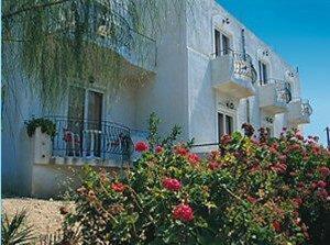 een groot wit gebouw met bloemen ervoor bij Senia Studios in Agia Marina Aegina