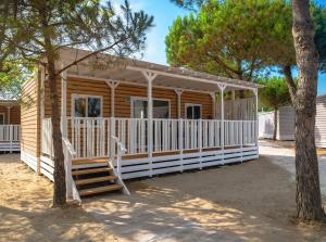 eine Holzhütte mit einer Veranda und einer Treppe vor dem Haus in der Unterkunft Sentido Punta Marina Premium Pini in Punta Marina