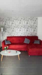 ein rotes Sofa im Wohnzimmer mit einem Tisch in der Unterkunft Petite maison indépendante in Bulgnéville