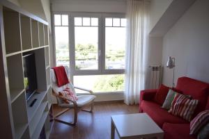 ein Wohnzimmer mit einem roten Sofa und einem Fenster in der Unterkunft Apartamentos Somo1 in Somo