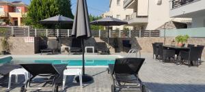 - une piscine avec des chaises, des tables et un parasol dans l'établissement Villa Peskena's, à Potamós