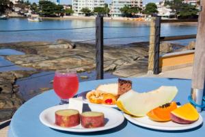 Hotel Pontal das Rochas في إيريري: طاولة مع طبقين من الطعام ومشروب