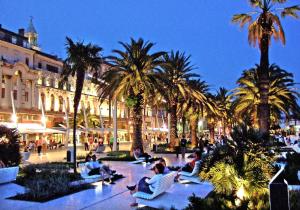 Un groupe de personnes assises sur une place bordée de palmiers dans l'établissement The One, à Split