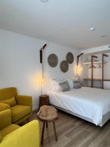 a bedroom with a white bed and a yellow chair at Alojamento White Rose Boutique in Zambujeira do Mar