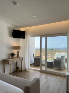 a bedroom with a bed and a desk and a view of the ocean at Alojamento White Rose Boutique in Zambujeira do Mar