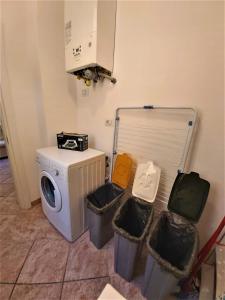 uma lavandaria com uma máquina de lavar roupa e três latas de lixo em Bologna Apartment em Bolonha