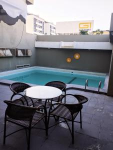 a pool with tables and chairs in front of a building at Pousada Boi Bumbá Praia in João Pessoa