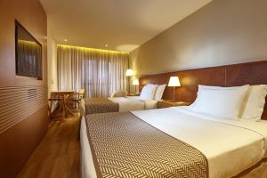 a hotel room with two beds and a table at PortoBay Rio de Janeiro in Rio de Janeiro