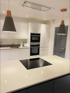 cocina con armarios blancos y encimera negra en Mia Property en Bristol