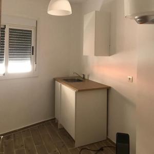 uma pequena cozinha com um lavatório e uma janela em French Apartment With restaurant em Taourirt
