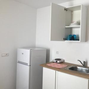 uma cozinha com um frigorífico branco e um lavatório em French Apartment With restaurant em Taourirt