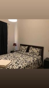 um quarto com uma cama com um edredão preto e branco em French Apartment With restaurant em Taourirt