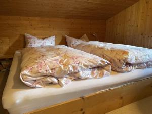 Cama en habitación de madera con 2 almohadas en Fewo 2 am Auweg, en Hirschegg