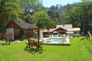 a backyard with a house and a swimming pool at Pousada Cabanas do Visconde in Visconde De Maua