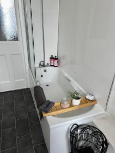 a bath tub with a wooden tray in a bathroom at A Shore Stay in Gourock